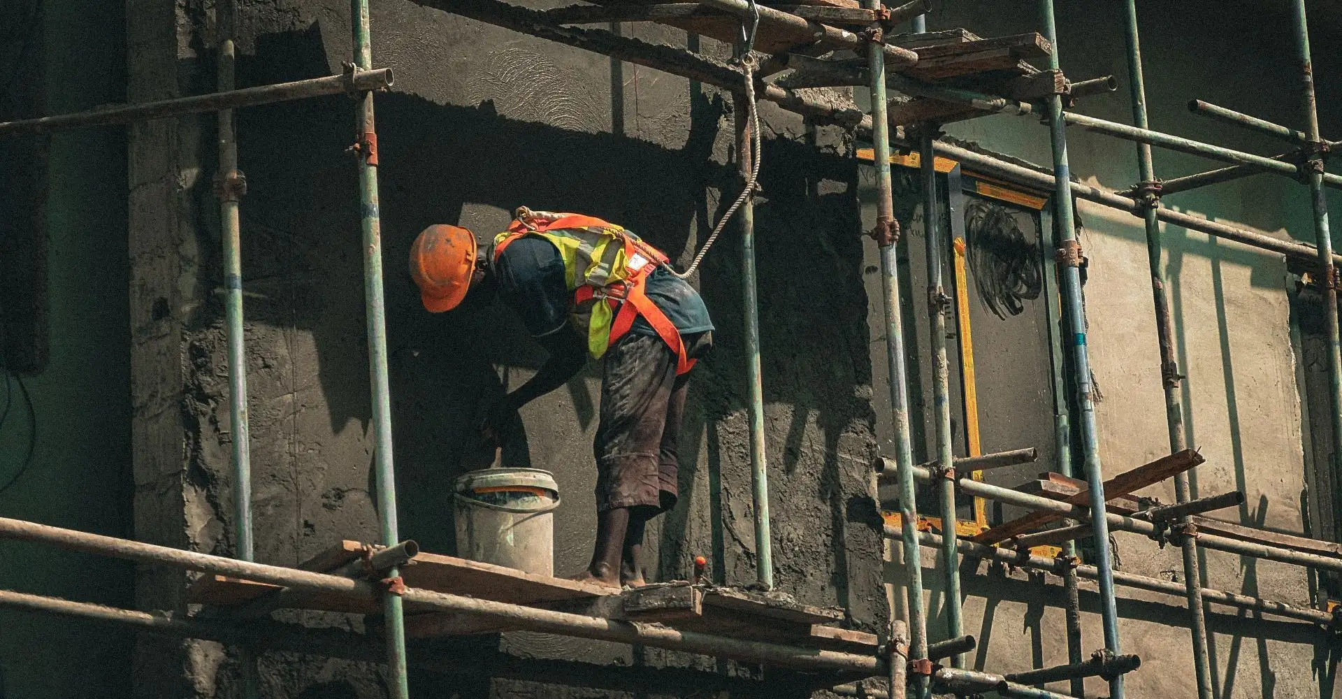 Trabajador con arnés y casco en un andamio