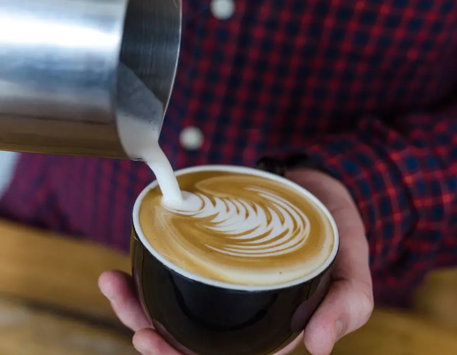Barista dibujando un corazón con leche en un café