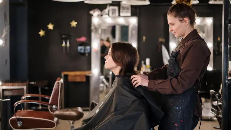 Peluquera cortando el cabello a una clienta en un salón moderno