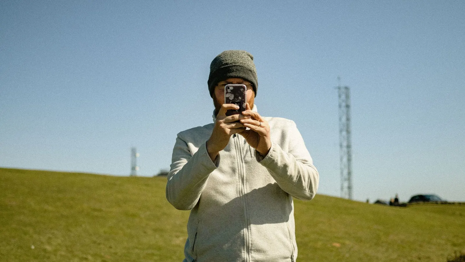 Hombre con gorro usando su celular al aire libre en una zona rural