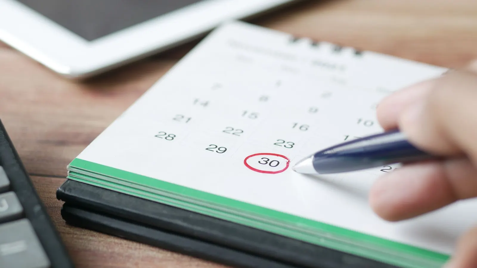 Mano marcando una fecha en un calendario de escritorio