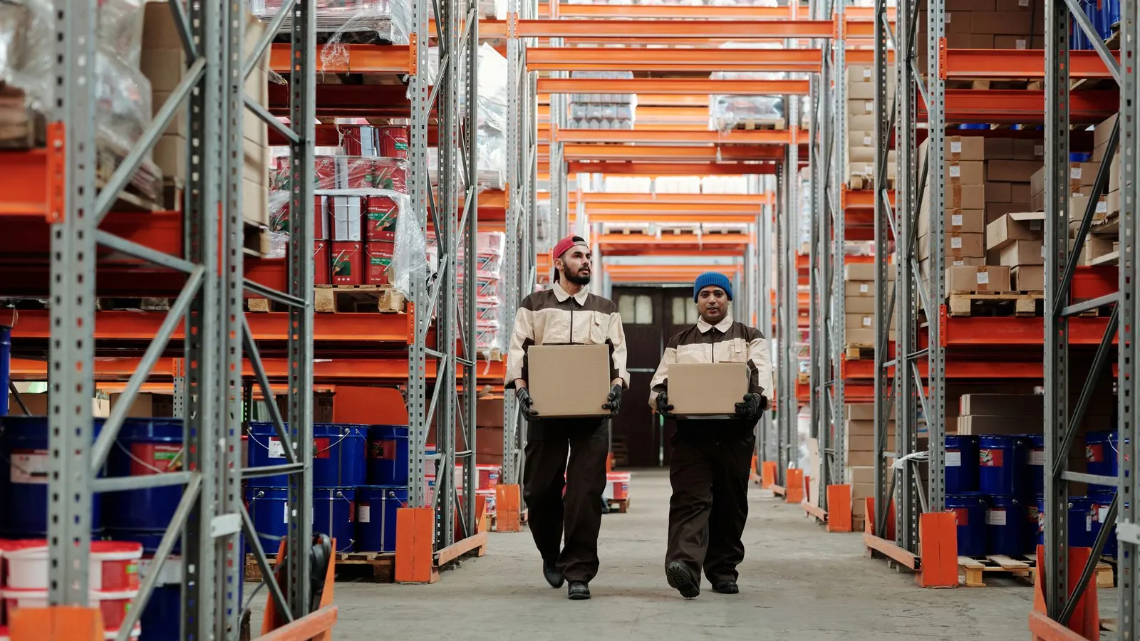 Trabajadores llevando cajas entre estanterías en un depósito