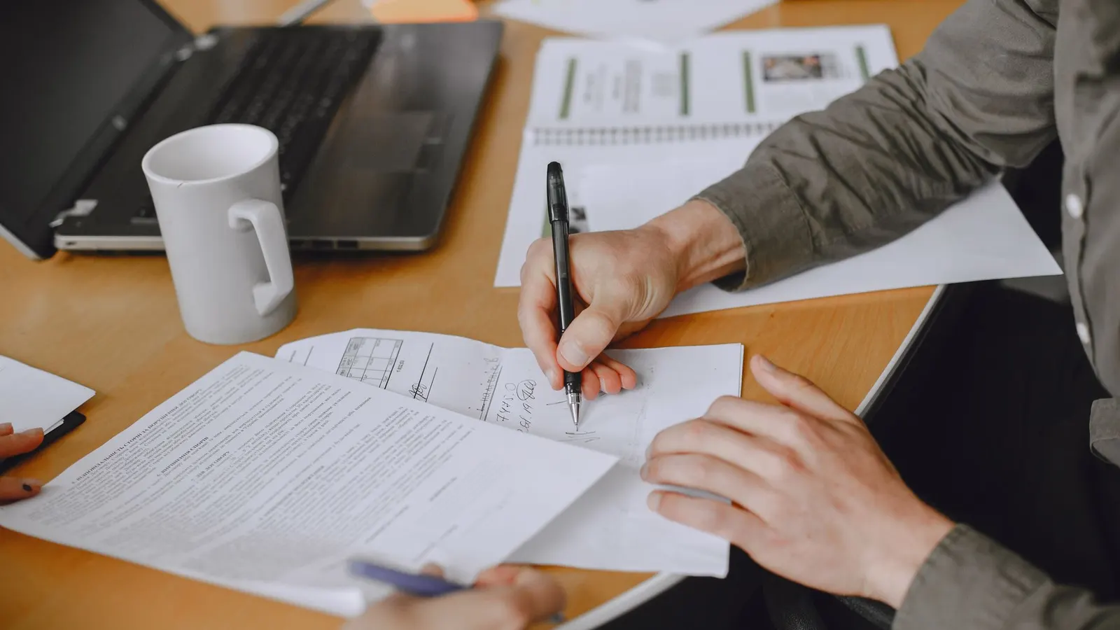 Personas firmando un acuerdo en una reunión de negocios