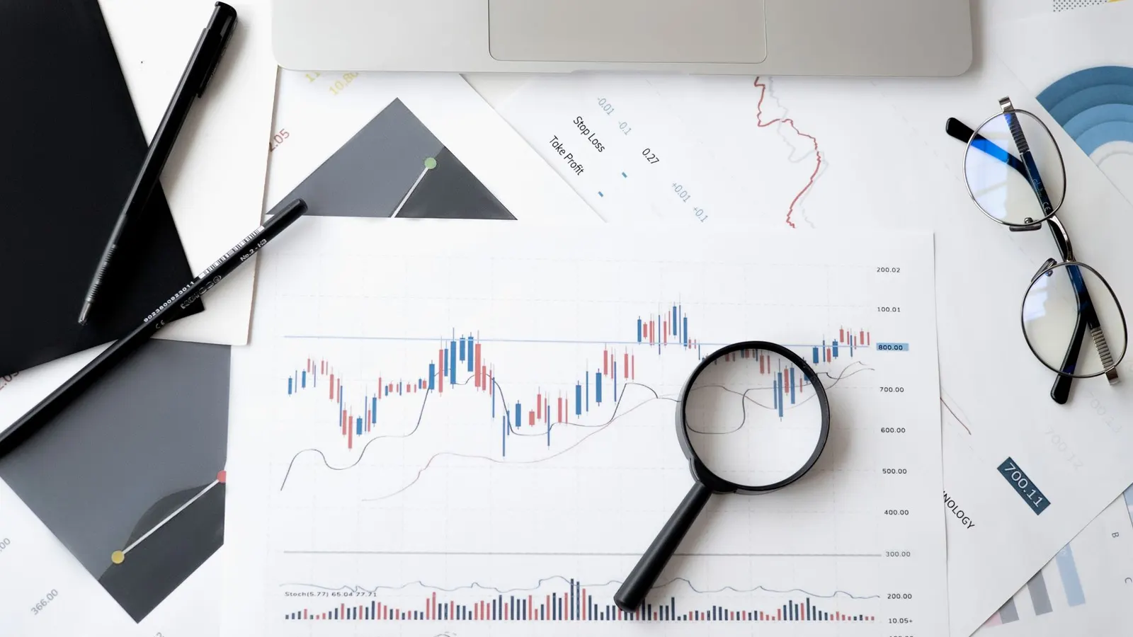 Lupa sobre documentos de análisis de mercado con gráficos