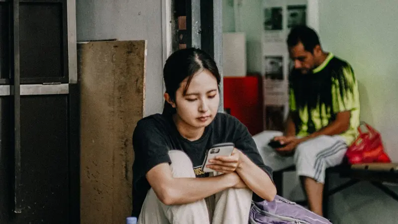 Joven esperando mientras mira su celular