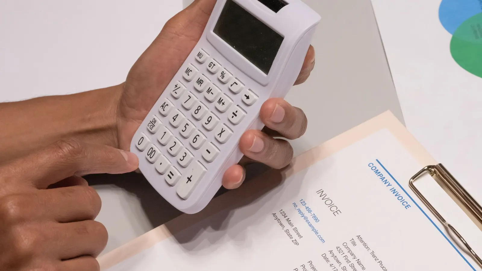 Manos usando una calculadora junto a una factura