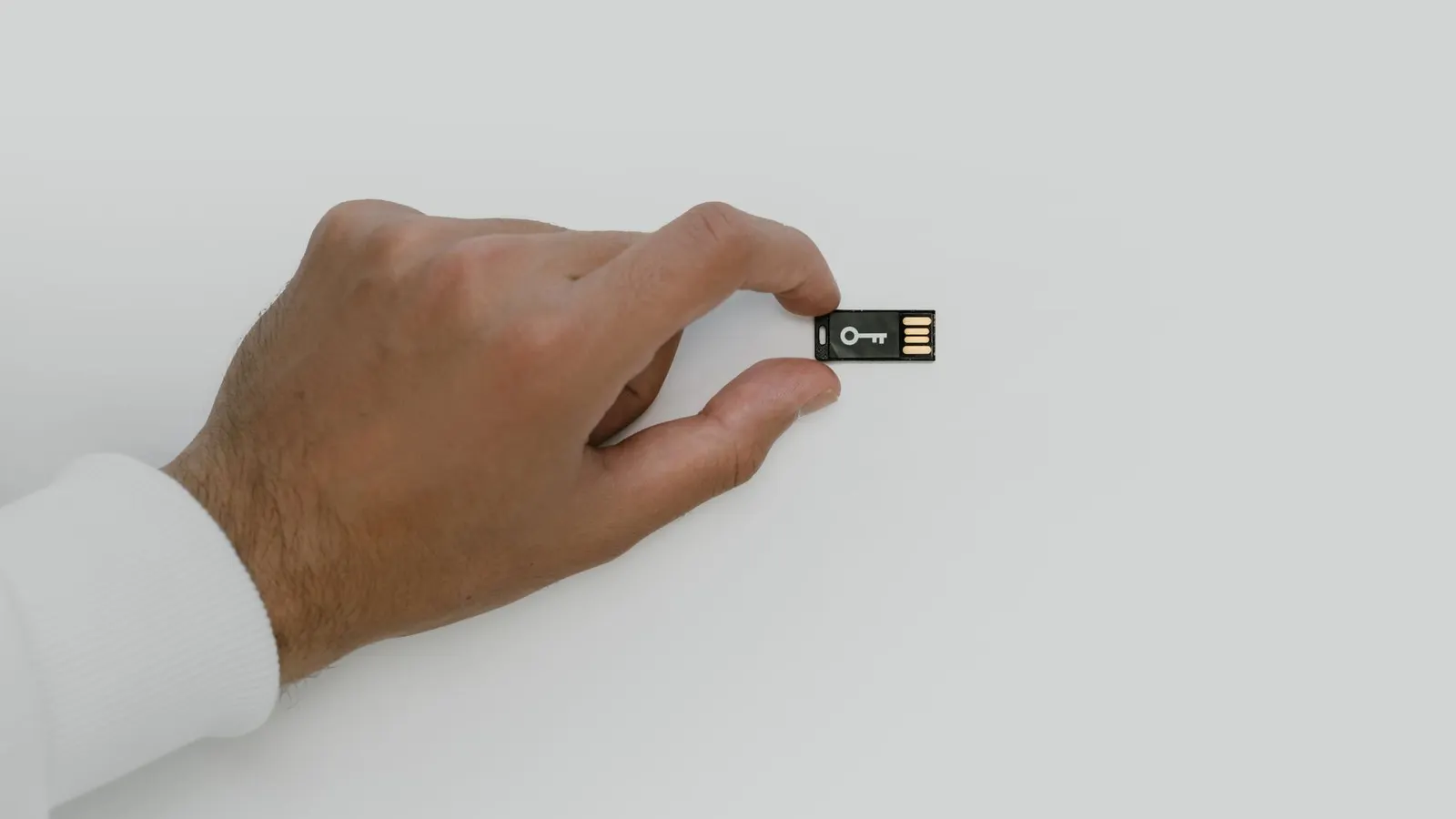 Una mano sostiene una llave USB de seguridad con el dibujo de una llave