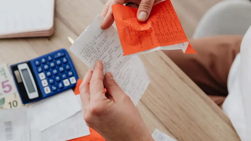 Papeles, facturas y una calculadora sobre un escritorio durante la revisión de las cuentas de un negocio
