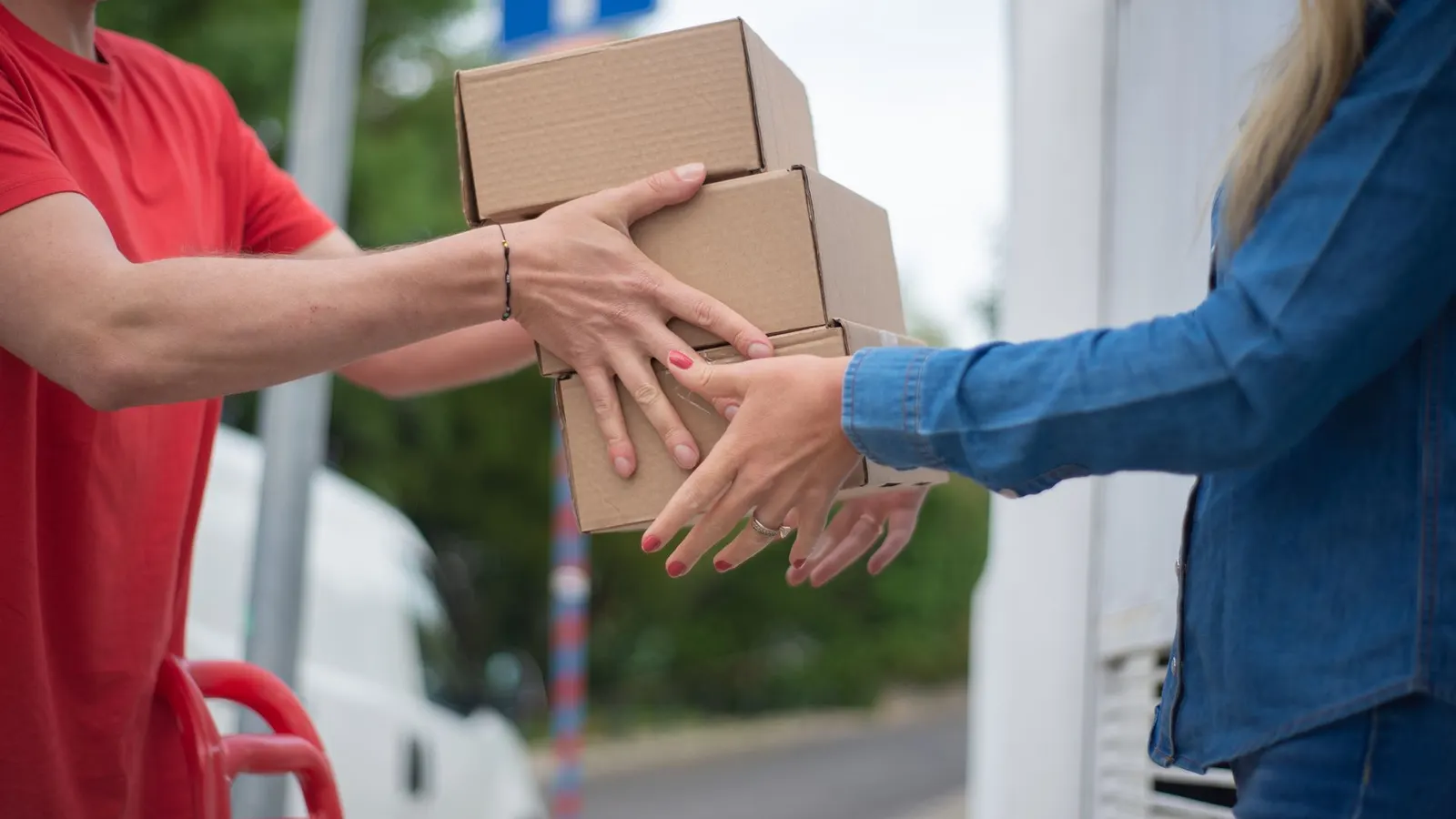 Un repartidor entrega tres cajas de cartón a una clienta en la puerta