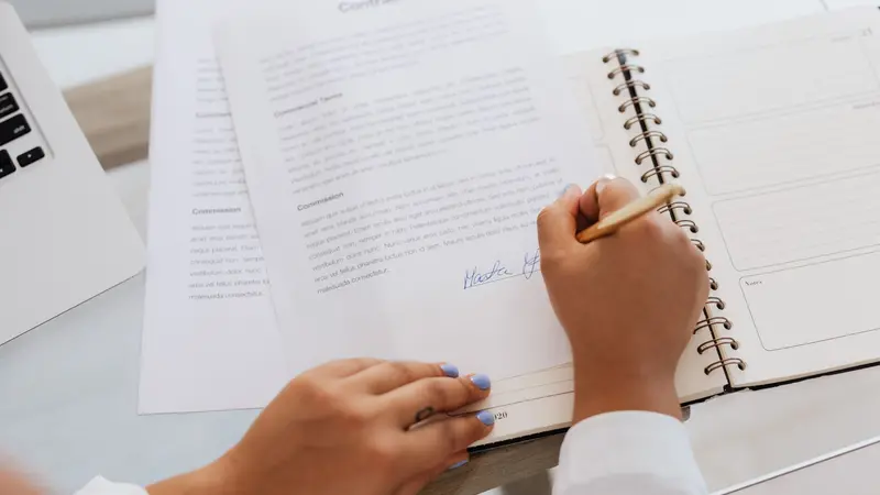 Persona firmando documentos legales en una oficina moderna