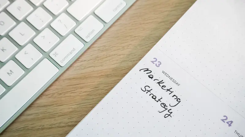 Persona planificando un calendario de marketing con notas adhesivas en una pizarra