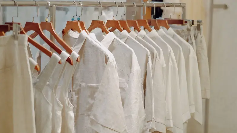 Diseñadora revisando prendas de ropa colgadas en un taller de moda
