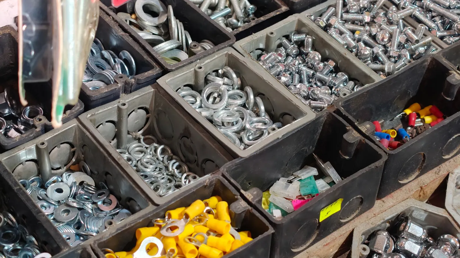 Surtido de tornillos y herrajes organizados en contenedores de una ferretería