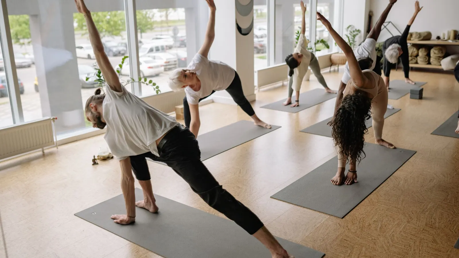 Clase grupal de estiramiento sobre colchonetas en el salón luminoso de un gimnasio
