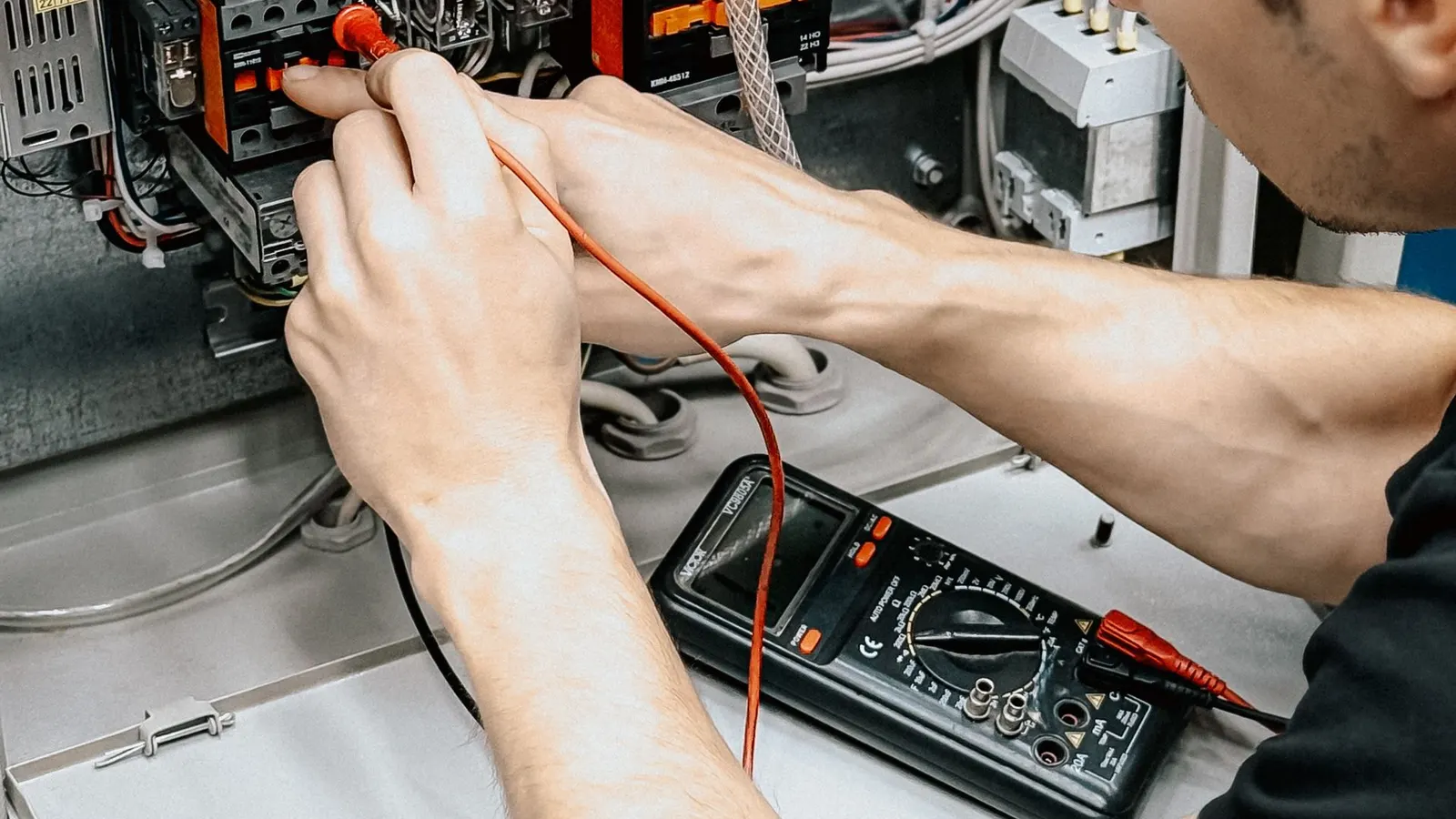 Eletricista diagnosticando um painel elétrico com um multímetro