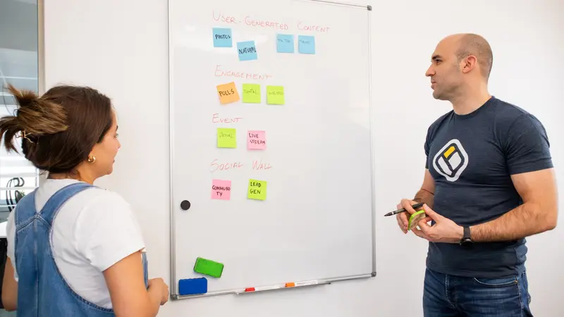 Equipo de trabajo anotando ideas en una pizarra durante una reunión en una oficina pequeña