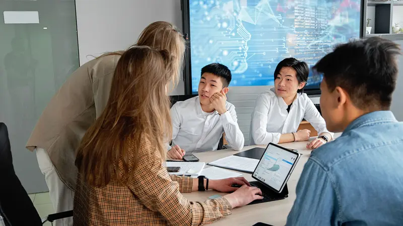 Persona sonriente usando una laptop con un asistente de inteligencia artificial en una oficina pequeña