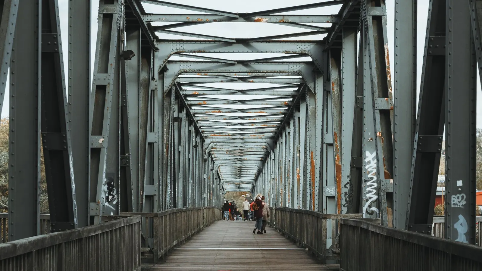 Puente peatonal moderno visto desde abajo con gente cruzando al atardecer