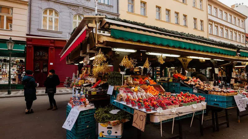 Un puesto de frutas en una calle de feria, con toda la mercadería expuesta y los precios escritos en cartelitos