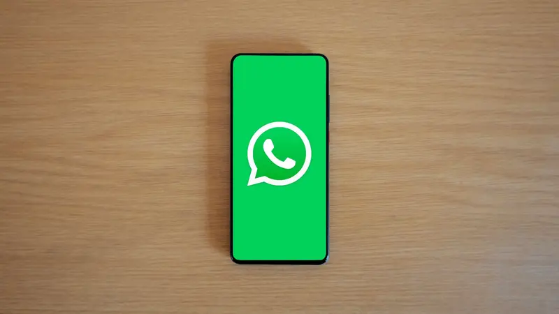 Logo de WhatsApp en la pantalla de un celular sobre fondo de madera